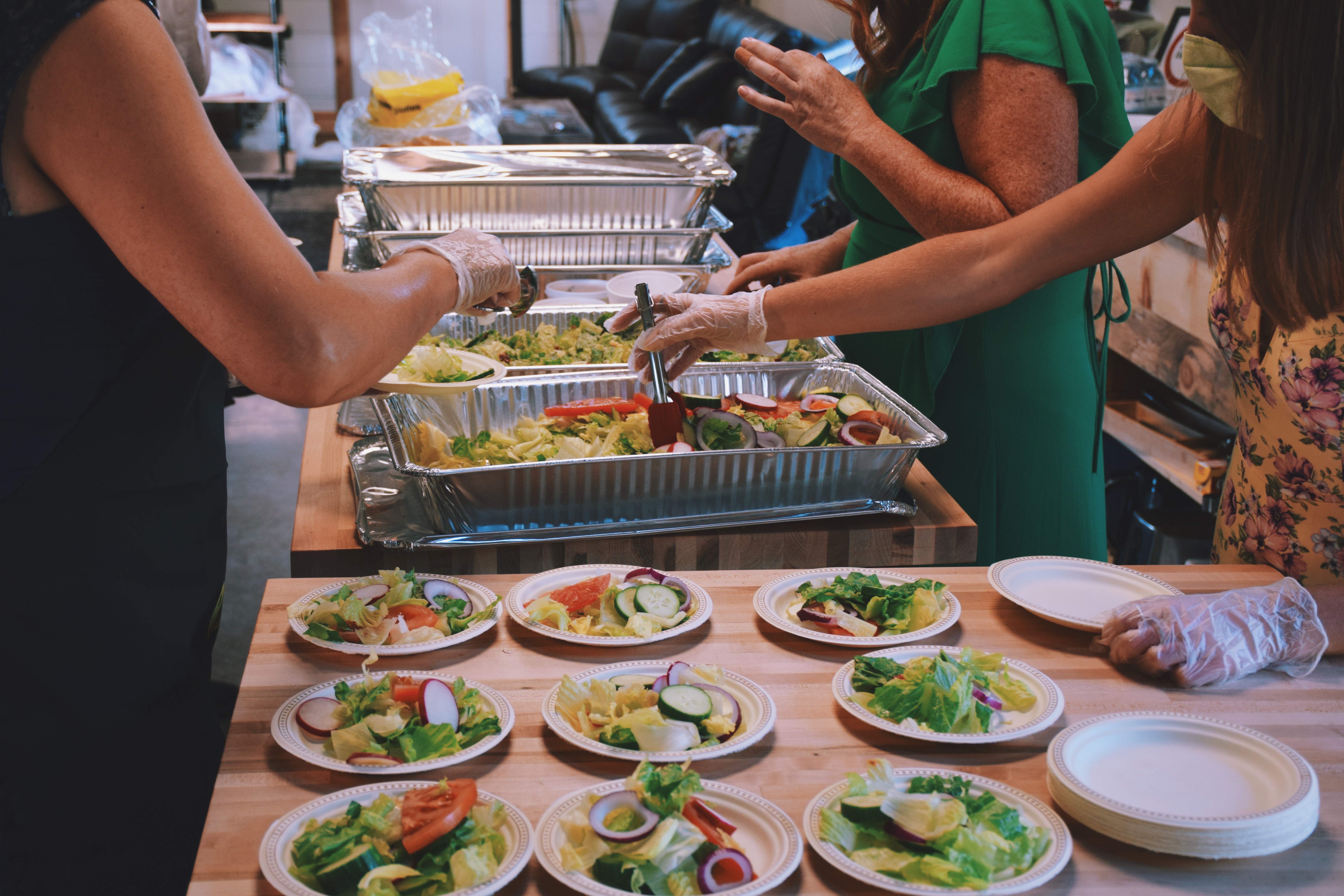 Women volunteers wearing face masks and gloves filling up plates with food at a community event