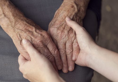 Old and young person holding hands. Elderly care and respect, selective focus