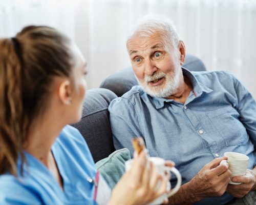 Doctor or nurse caregiver with senior man at home or nursing home