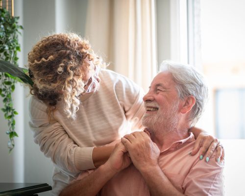 Portrait of middle aged woman lovingly caring for her elderly father at home while spending time together